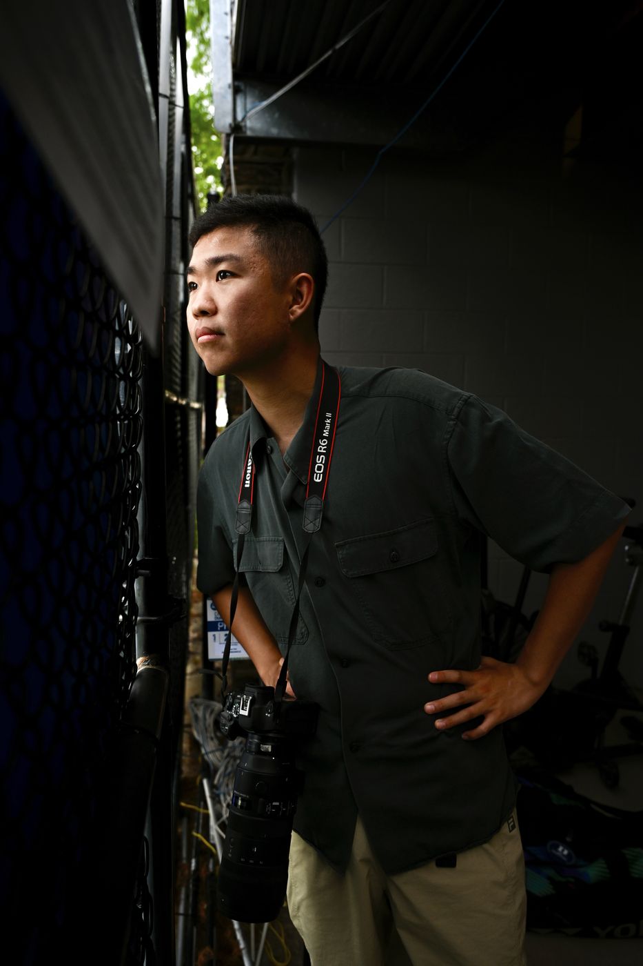 Thomas holding a camera with a long lens, looking out from a dark stadium tunnel