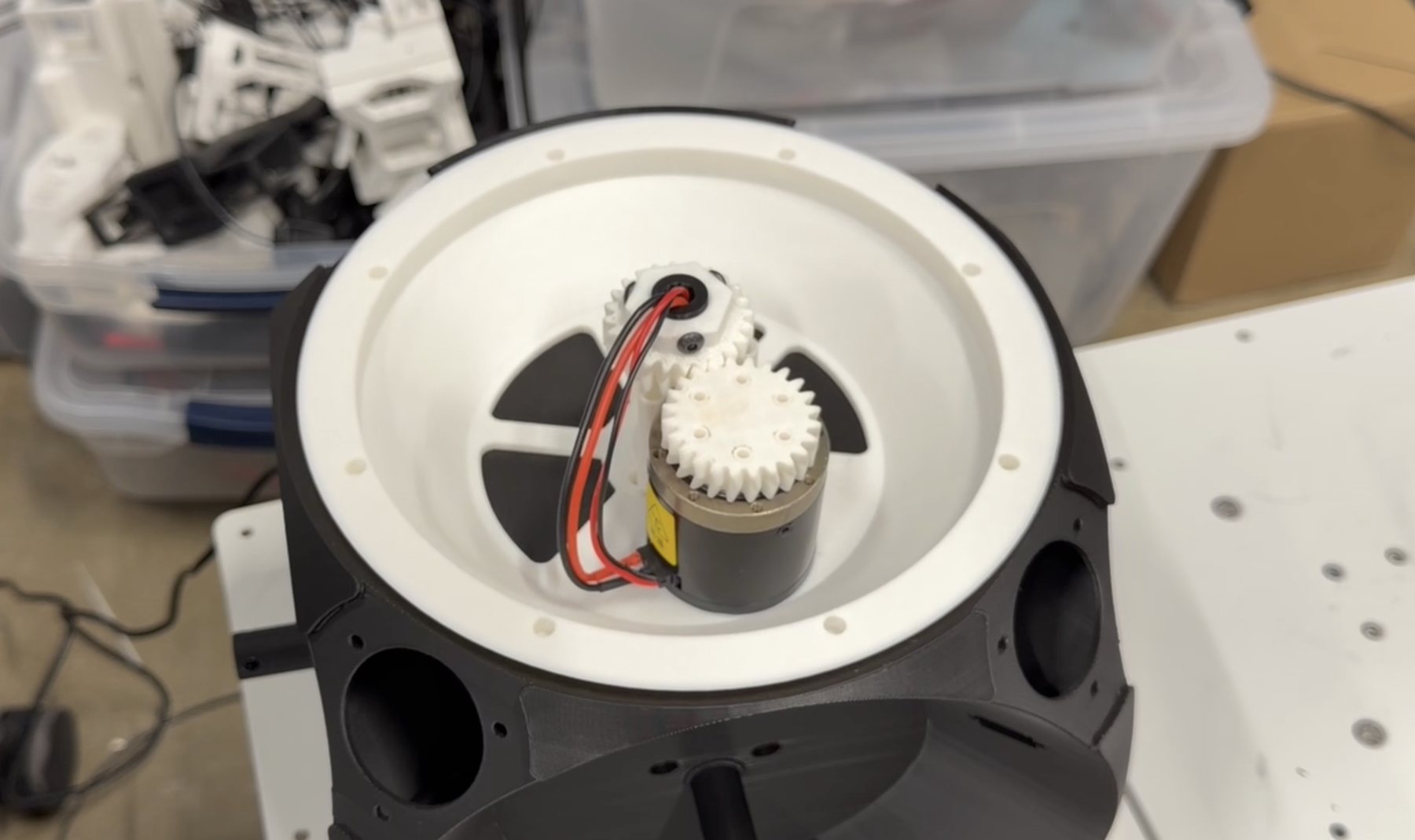 A geared motor mounted inside an open white shell section on the workbench
